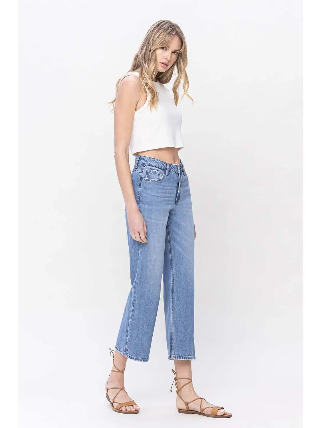 woman wearing HIGH RISE straight DAD denim JEANS  with white crop tank and sandals in front of a white background