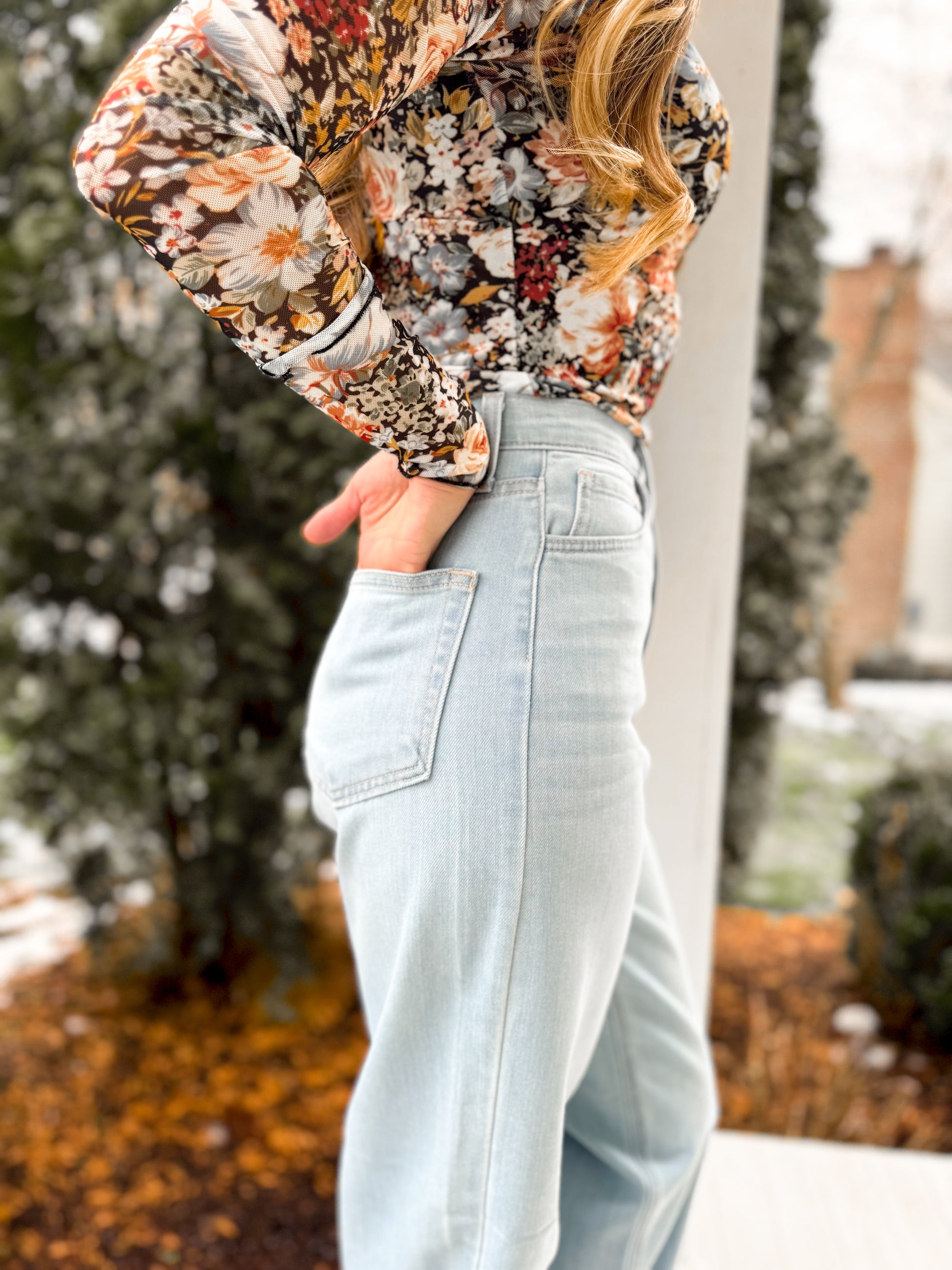 closeup side view of woman wearing light wash  high waisted retro straight denim jeans with a floral mesh top 